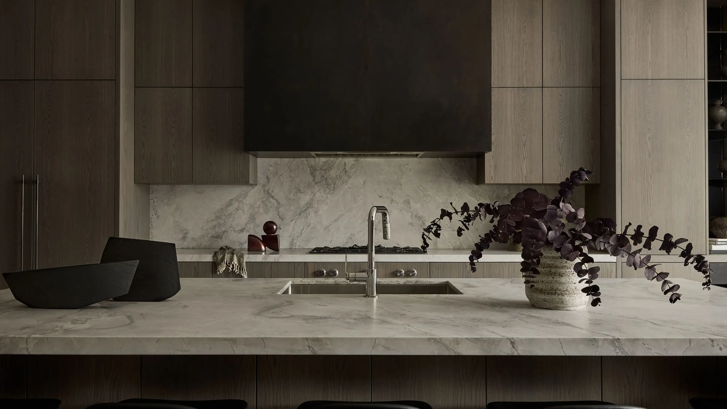 McMaster Avenue: a rift-cut oak kitchen with a quartzite island, full-height stone backsplash, and a recessed hood surround, Toronto.